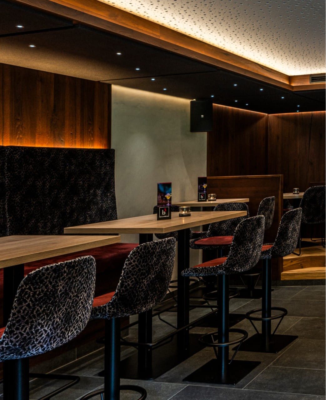 Eleganter Barbereich mit hohen Tischen und bequemen Barhockern in der B3 Bar in Großarl