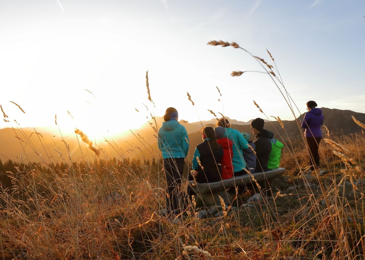 Wanderer genießen gemeinsam den Sonnenuntergang auf einer Bank in den Bergen © Tourismusverband Großarltal