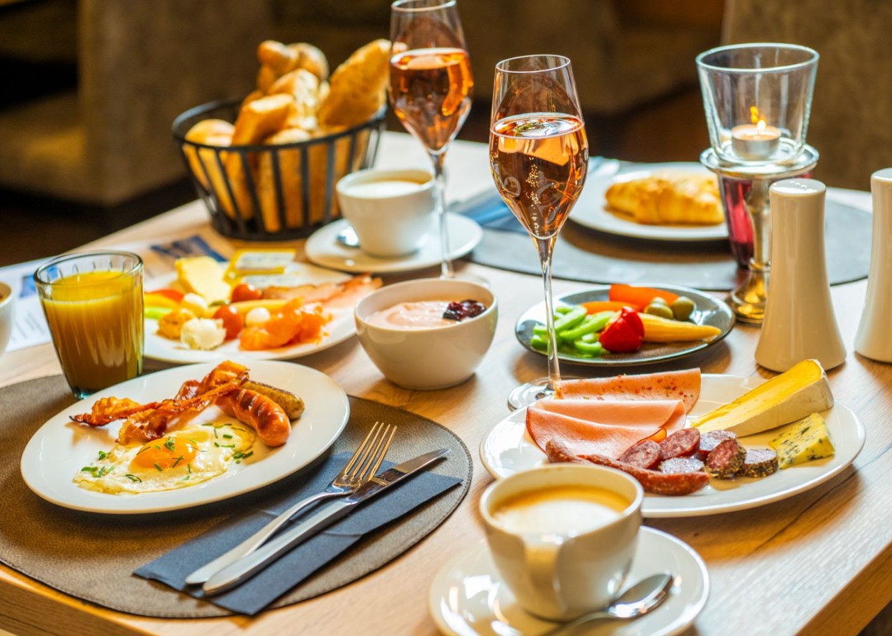  Reichhaltiges Frühstück mit Eierspeisen, frischem Brot, Aufschnitt und Getränken